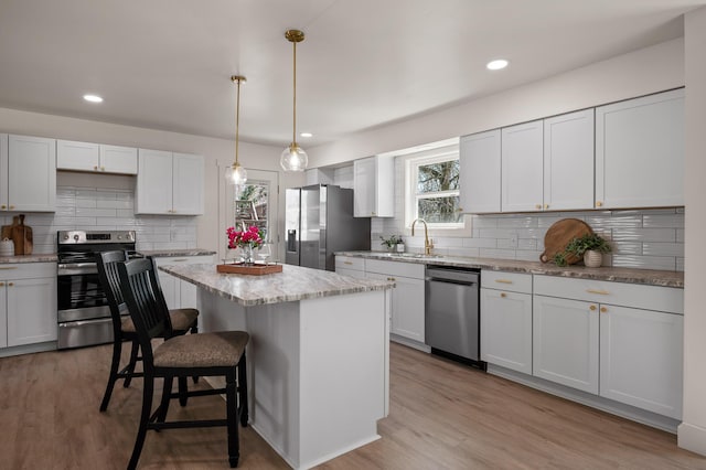 kitchen featuring a center island, light wood-type flooring, light stone counters, a kitchen breakfast bar, and stainless steel appliances