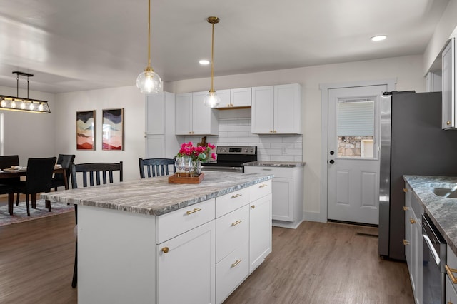 kitchen with backsplash, a breakfast bar area, wood finished floors, white cabinets, and stainless steel appliances