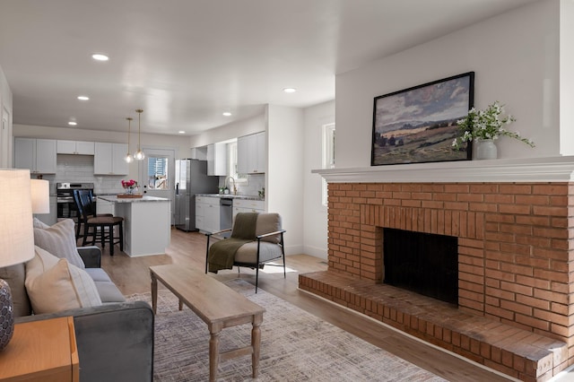 living area featuring recessed lighting, baseboards, a fireplace, and light wood finished floors