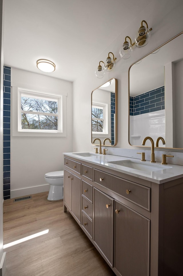 bathroom featuring visible vents, toilet, wood finished floors, and a sink