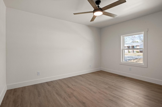 spare room featuring visible vents, ceiling fan, baseboards, and wood finished floors