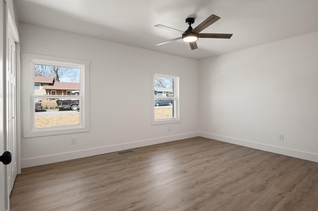 spare room featuring plenty of natural light, baseboards, and wood finished floors