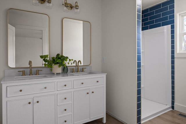 bathroom with double vanity, visible vents, wood finished floors, and a sink