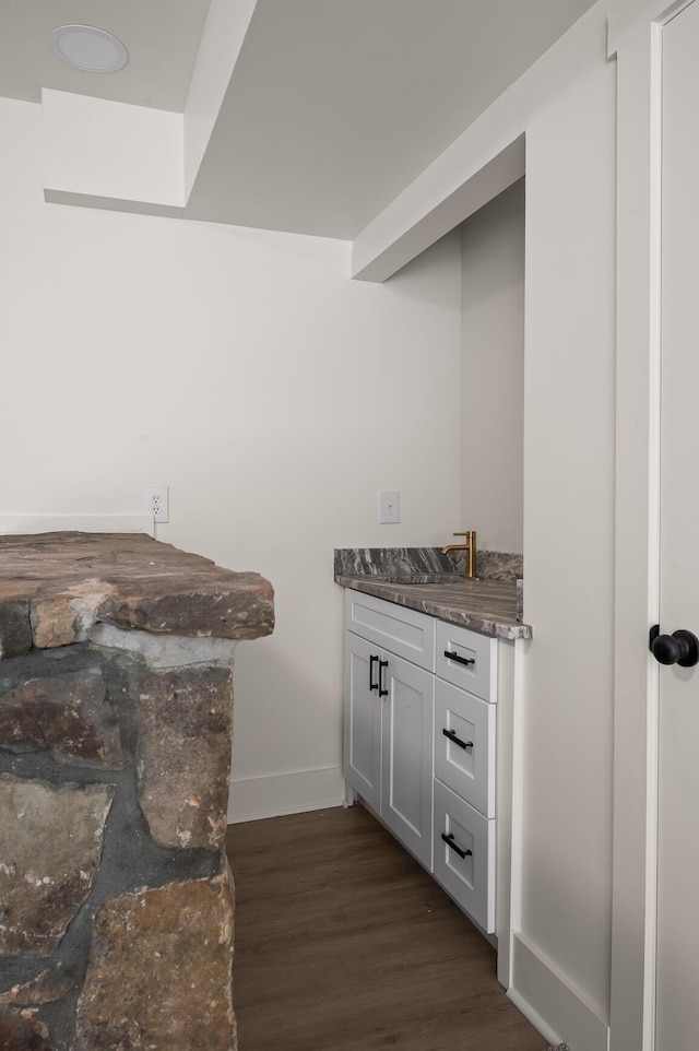 bar with dark wood-type flooring, baseboards, and a sink