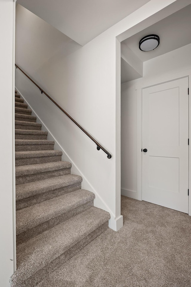 stairway featuring baseboards and carpet floors