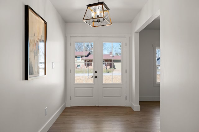 doorway to outside with french doors, baseboards, wood finished floors, and a chandelier