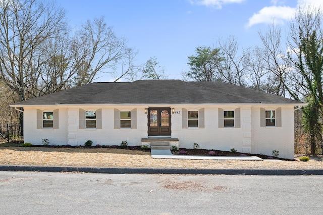 view of front of house featuring french doors, brick siding, a shingled roof, and fence