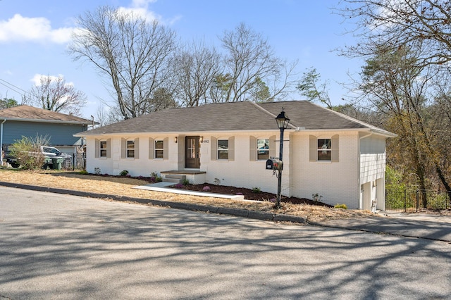 ranch-style house featuring fence, brick siding, and a shingled roof