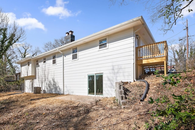 back of property with a wooden deck, central AC unit, and a chimney