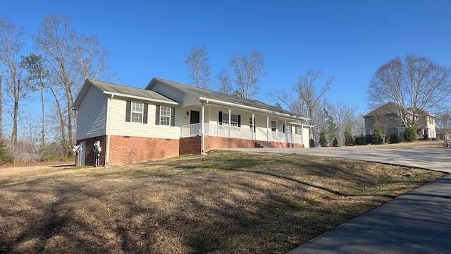 ranch-style house with a porch, concrete driveway, and a front lawn