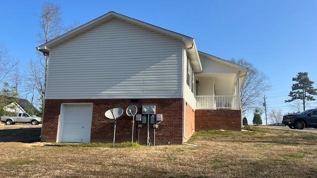 view of home's exterior featuring brick siding, a lawn, and an attached garage