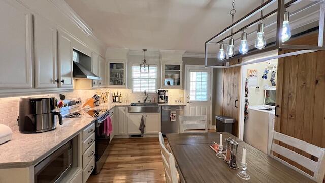 kitchen with tasteful backsplash, stainless steel appliances, wall chimney exhaust hood, and a sink