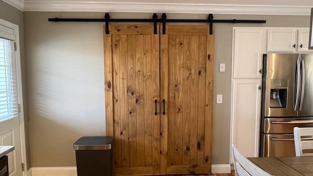 kitchen featuring white cabinetry, crown molding, a barn door, and stainless steel fridge with ice dispenser