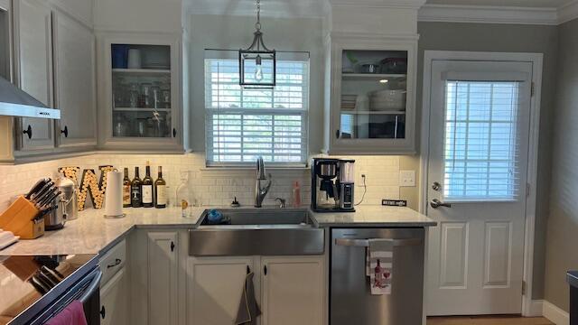 kitchen with a sink, light countertops, crown molding, and stainless steel dishwasher