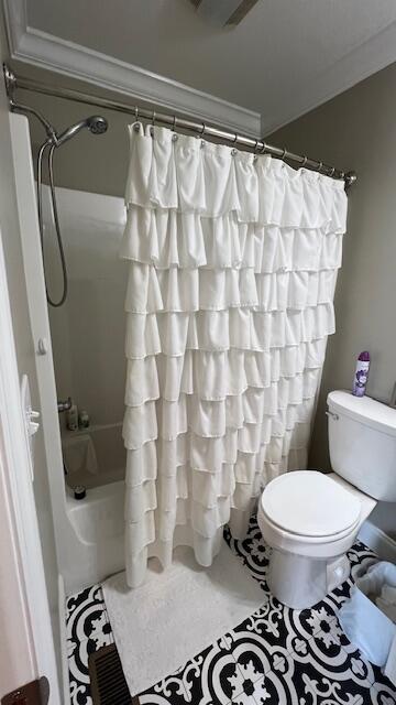 bathroom with toilet, crown molding, and shower / bath combo