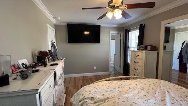 bedroom with ceiling fan, crown molding, baseboards, and wood finished floors