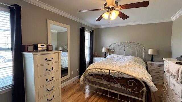 bedroom featuring light wood-type flooring, baseboards, a ceiling fan, and crown molding