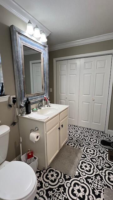 half bathroom featuring vanity, crown molding, and toilet