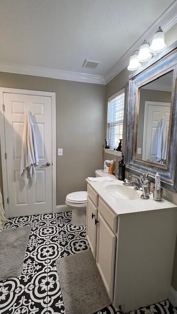 bathroom with vanity, visible vents, tile patterned flooring, crown molding, and toilet