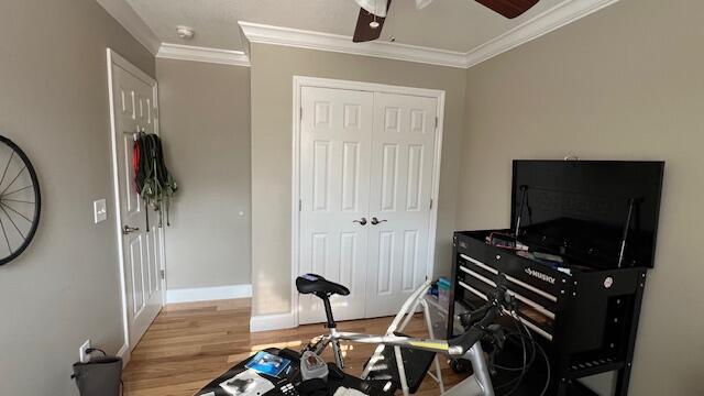 interior space featuring crown molding, wood finished floors, a closet, and baseboards