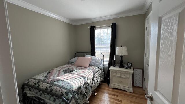 bedroom with light wood-type flooring and crown molding