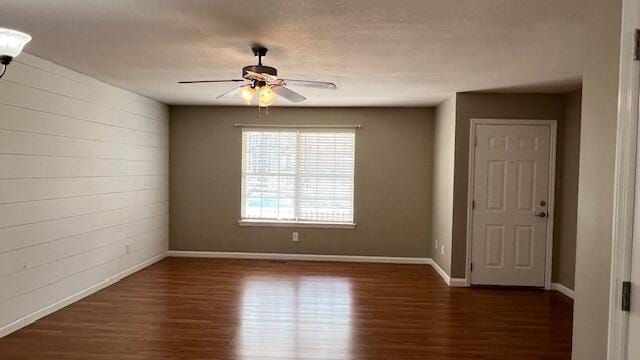 spare room featuring baseboards, wood finished floors, and a ceiling fan