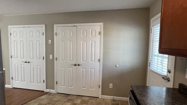 unfurnished bedroom with baseboards, multiple windows, and two closets