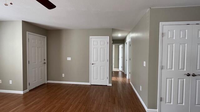 interior space with ceiling fan, baseboards, two closets, and wood finished floors