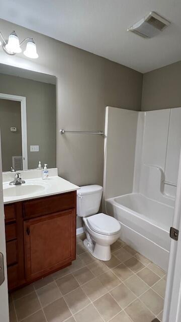 full bath with visible vents, toilet, vanity, and tile patterned flooring