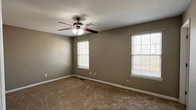 carpeted empty room featuring ceiling fan and baseboards