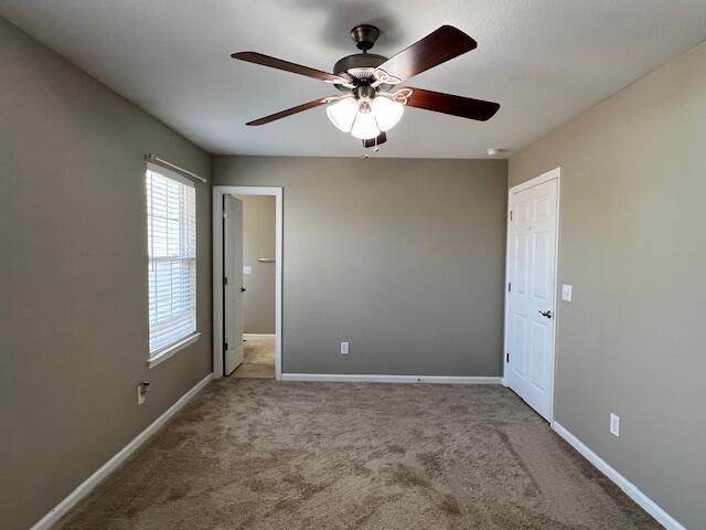 unfurnished bedroom with baseboards, carpet, and a ceiling fan