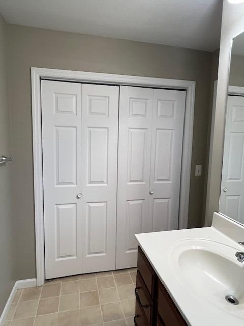 bathroom featuring vanity, baseboards, a closet, and tile patterned flooring