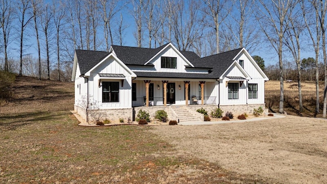 modern farmhouse with board and batten siding, a front lawn, covered porch, metal roof, and a standing seam roof