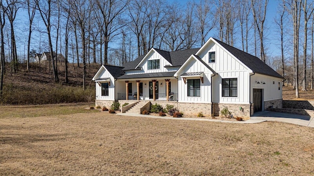 modern farmhouse with a front yard, a standing seam roof, covered porch, board and batten siding, and metal roof