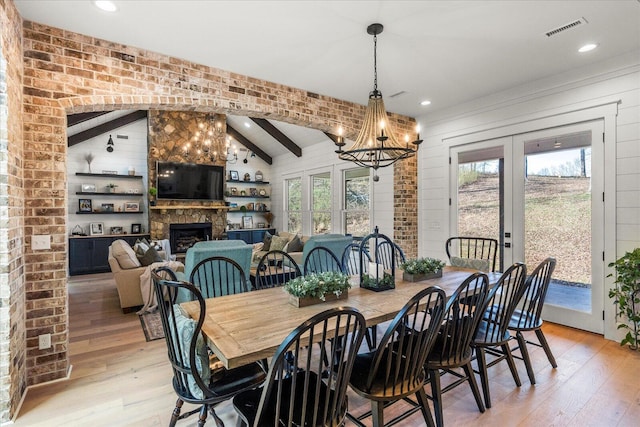 dining area with visible vents, a fireplace, french doors, and light wood finished floors