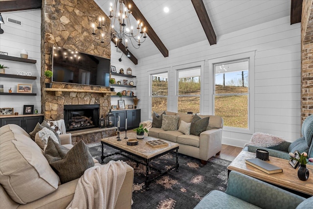 living area featuring beam ceiling, plenty of natural light, a stone fireplace, and wood finished floors