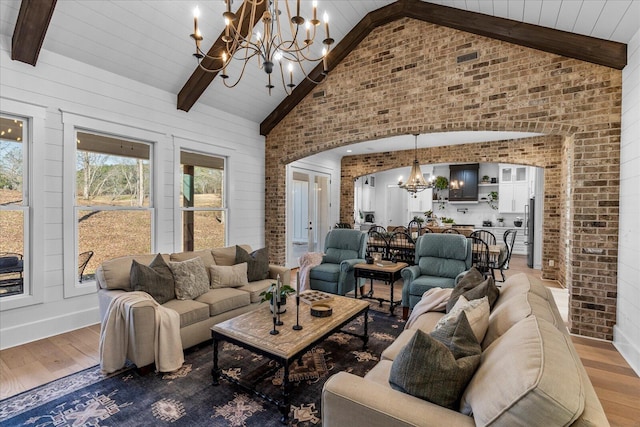 living room featuring a chandelier, beam ceiling, and light wood-style flooring