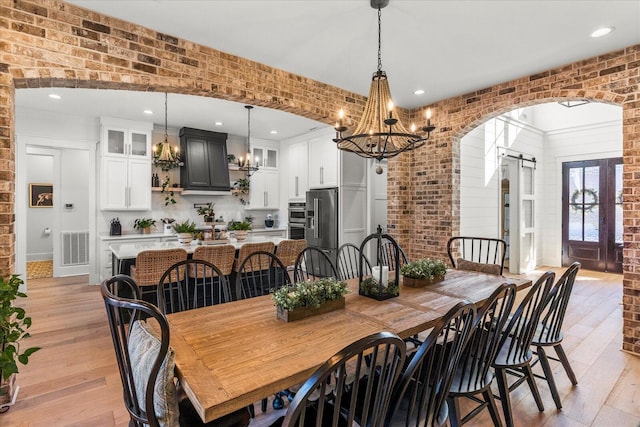 dining space featuring arched walkways, visible vents, brick wall, and a barn door