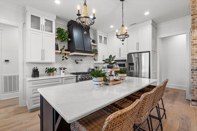 kitchen featuring visible vents, appliances with stainless steel finishes, a center island, and light stone countertops