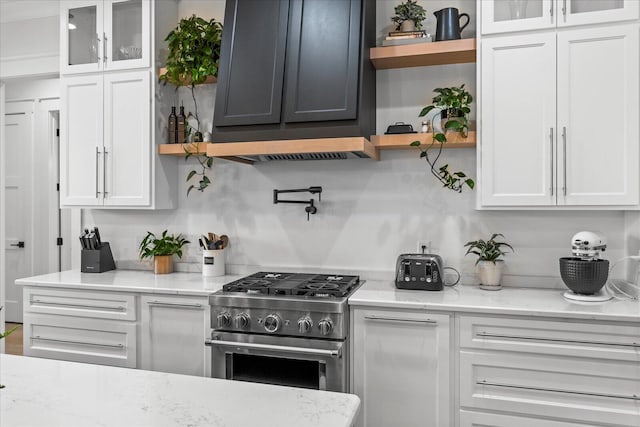 kitchen with range hood, white cabinets, high end stainless steel range, and open shelves