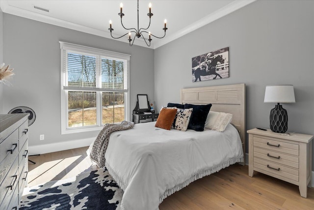 bedroom with a chandelier, ornamental molding, and light wood finished floors