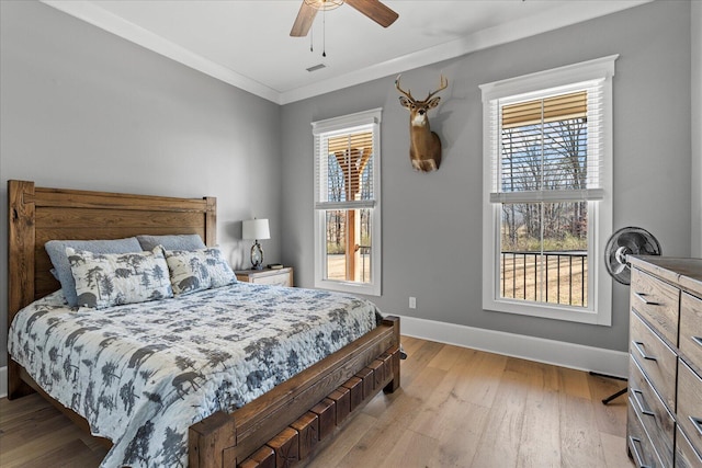 bedroom featuring light wood finished floors, multiple windows, baseboards, and ornamental molding