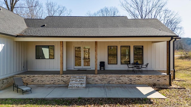 exterior space with a patio area, french doors, board and batten siding, and a shingled roof