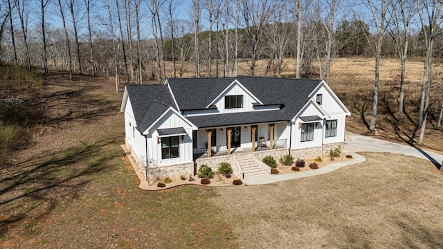 modern farmhouse style home featuring board and batten siding, a shingled roof, a front lawn, a porch, and a standing seam roof