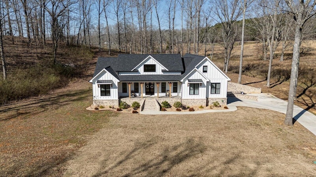 modern farmhouse style home featuring covered porch, board and batten siding, and a front yard