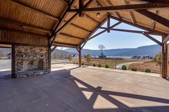 view of patio featuring a mountain view and an outdoor stone fireplace