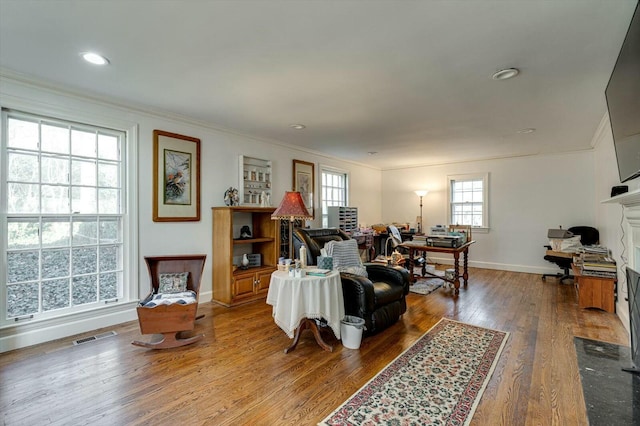 living room with baseboards, visible vents, recessed lighting, ornamental molding, and wood-type flooring