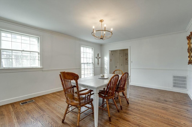 dining space with a chandelier, visible vents, crown molding, and wood finished floors