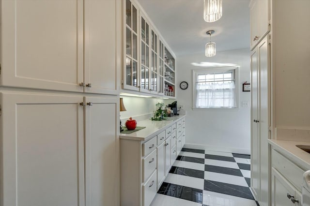 kitchen featuring white cabinetry, light countertops, glass insert cabinets, and dark floors