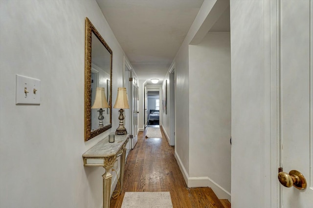 hall with dark wood-style floors and baseboards